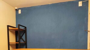 A room with a blue wall, a wooden reception desk with the word "Soul" in red letters, and a black metal shelf unit. - Soul Hostel 2 (Sao Paulo)