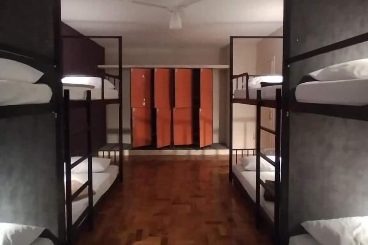 Ein Hotelzimmer mit Etagenbetten, Holzdielenboden und Deckenventilator.