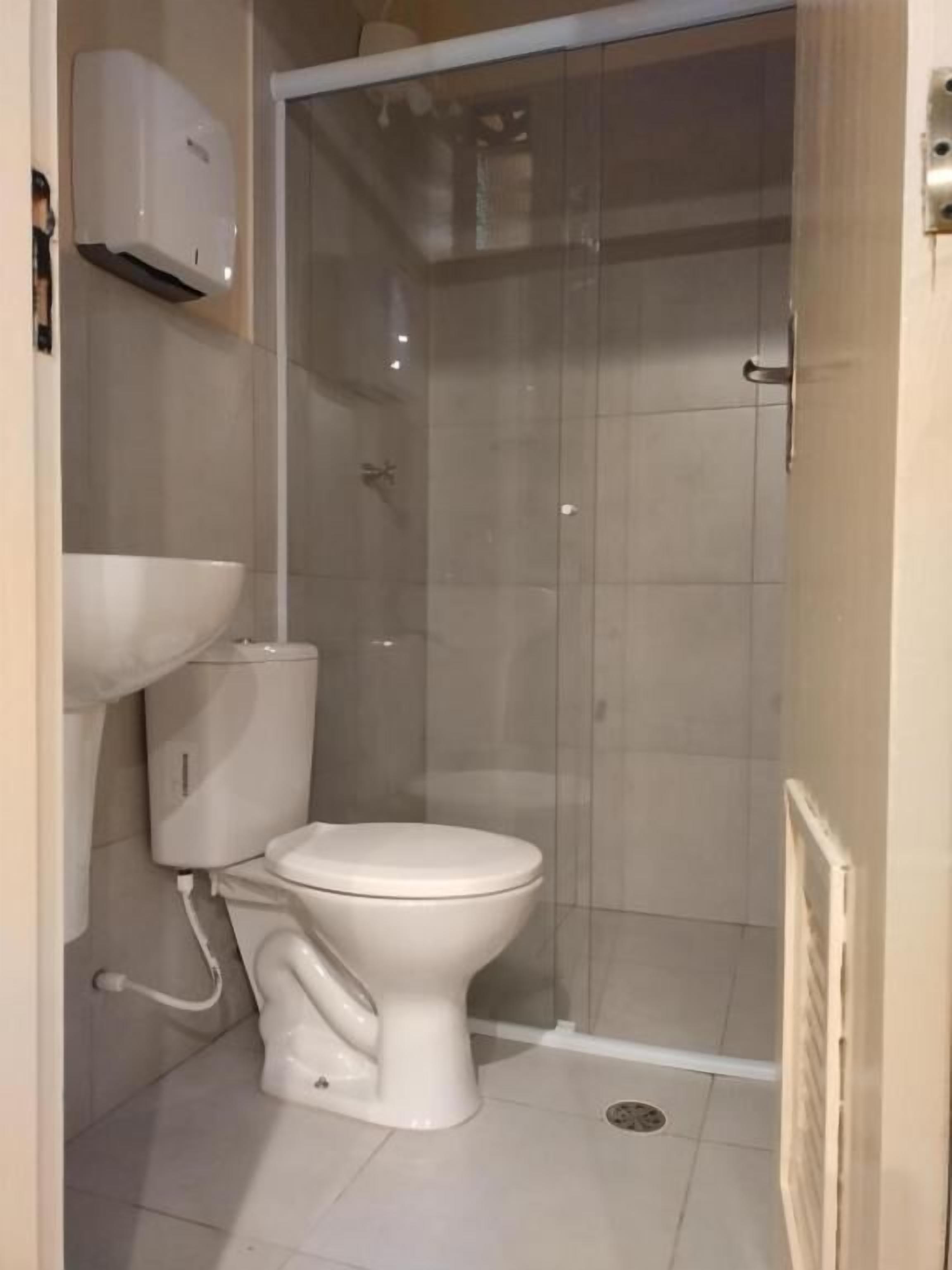Une salle de bain équipée de toilettes, d’une douche et d’un climatiseur fixé au mur.