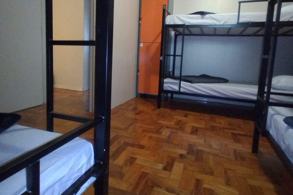 Ein Schlafsaalzimmer mit Etagenbetten, Holzdielenboden, einer Tür und einer Wand mit einer roten Nummer.