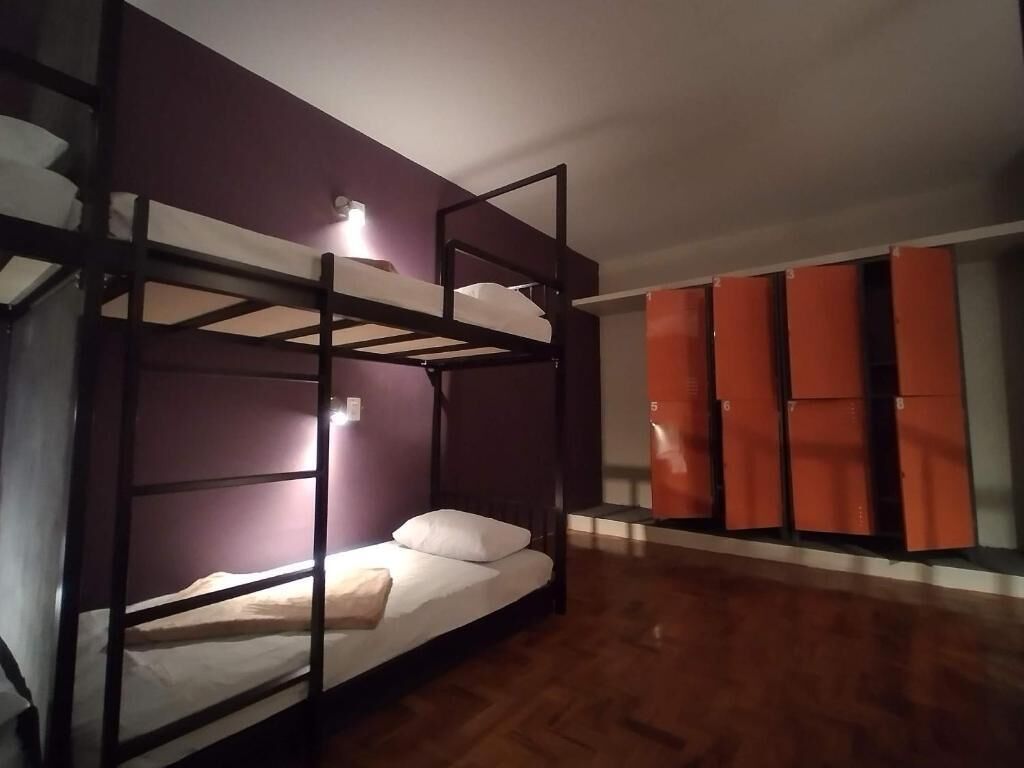 A bunk bed room with a wooden floor, a purple wall, and a wardrobe with orange doors.