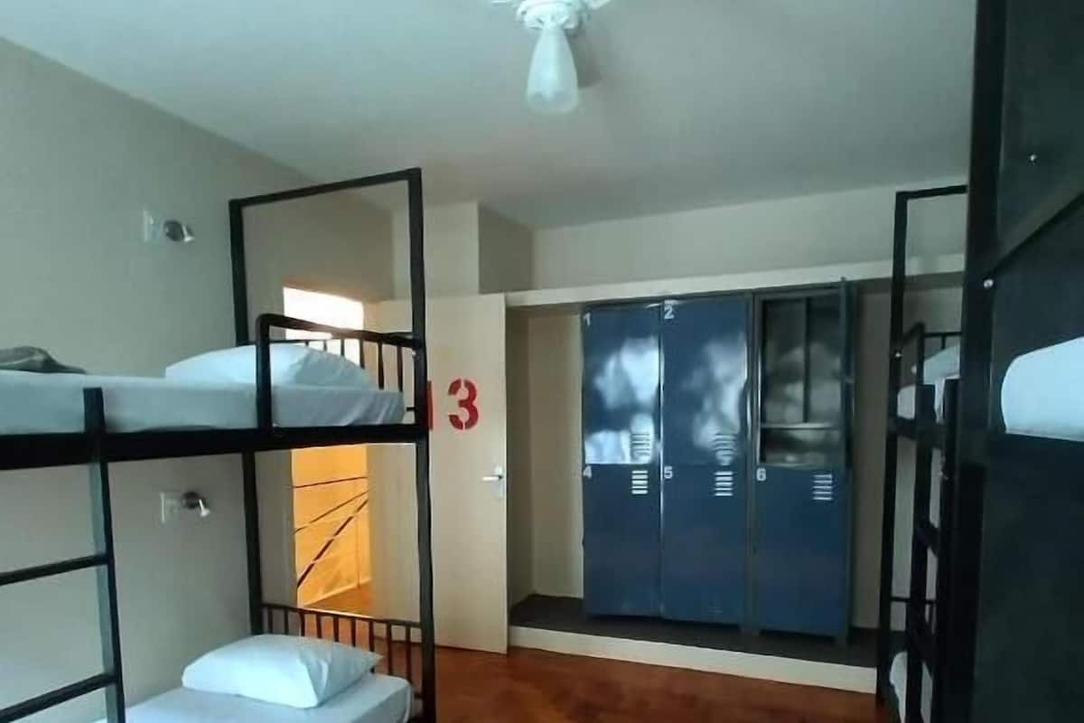 Ein Schlafsaalzimmer mit Etagenbetten, einem Deckenventilator und einem Holzboden.