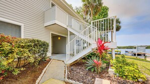 A two-story house with a white exterior, a covered porch, and a staircase leading to the second floor. - St Johns River Retreat in Welaka w/ Dock Access (Welaka)