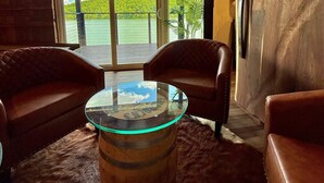 A room with leather sofas, a glass coffee table, and a wooden barrel. - 9 bdrm covered dock, firepit and large bar on water, Baltic hot tub, sleeps 26, (lafollette)