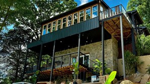 A modern house with a large deck, stone walls, and a waterfall. - 9 bdrm covered dock, firepit and large bar on water, Baltic hot tub, sleeps 26, (lafollette)