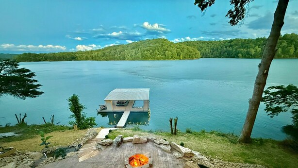 A lakeside property with a fire pit, outdoor seating, and a dock leading to a house. - 9 bdrm covered dock, firepit and large bar on water, Baltic hot tub, sleeps 26, (lafollette)