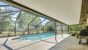 Een overdekt zwembad met uitzicht op de omgeving, een barbecue en tuinmeubilair.