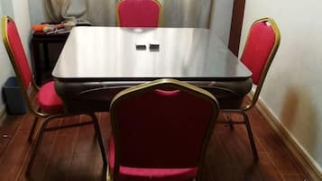 Una mesa rectangular de comedor con cuatro sillas, cada una con cojín rojo y estructura dorada.
