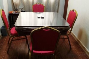 A rectangular dining table with four chairs, each with a red seat cushion and gold frame. - Tianyou Business Hotel (Wuyuan)