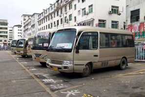 A row of beige minibuses parked in a lot with buildings in the background. - Tianyou Business Hotel (Wuyuan)
