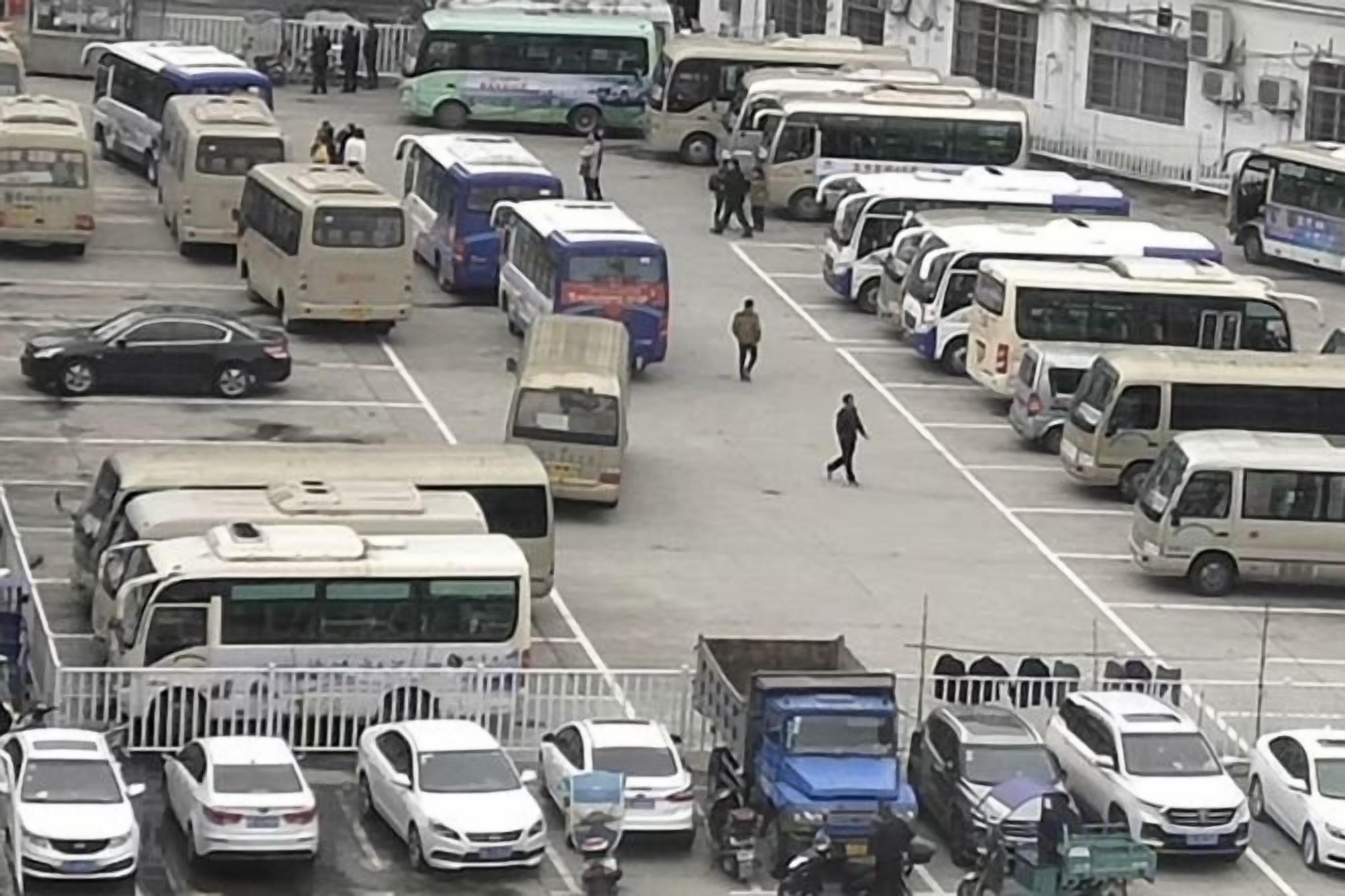 Un estacionamiento con varios autobuses y coches, que sugiere un centro de transporte.