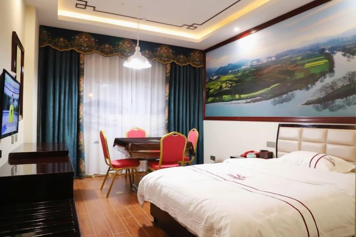 A hotel room with a bed, a desk, a chair, a television, and a painting on the wall.