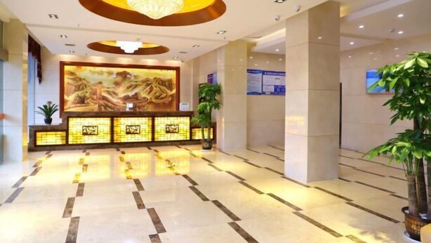 A lobby with a large reception desk, a chandelier, and a large painting on the wall.