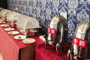 Disposição de buffet com estações de comida cobertas e toalha vermelha.
