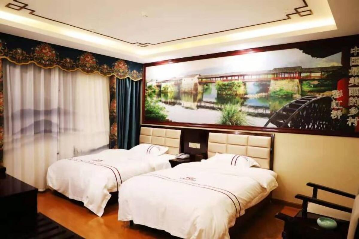 A hotel room with two beds, a large wall mural, a wooden headboard, and a small table.