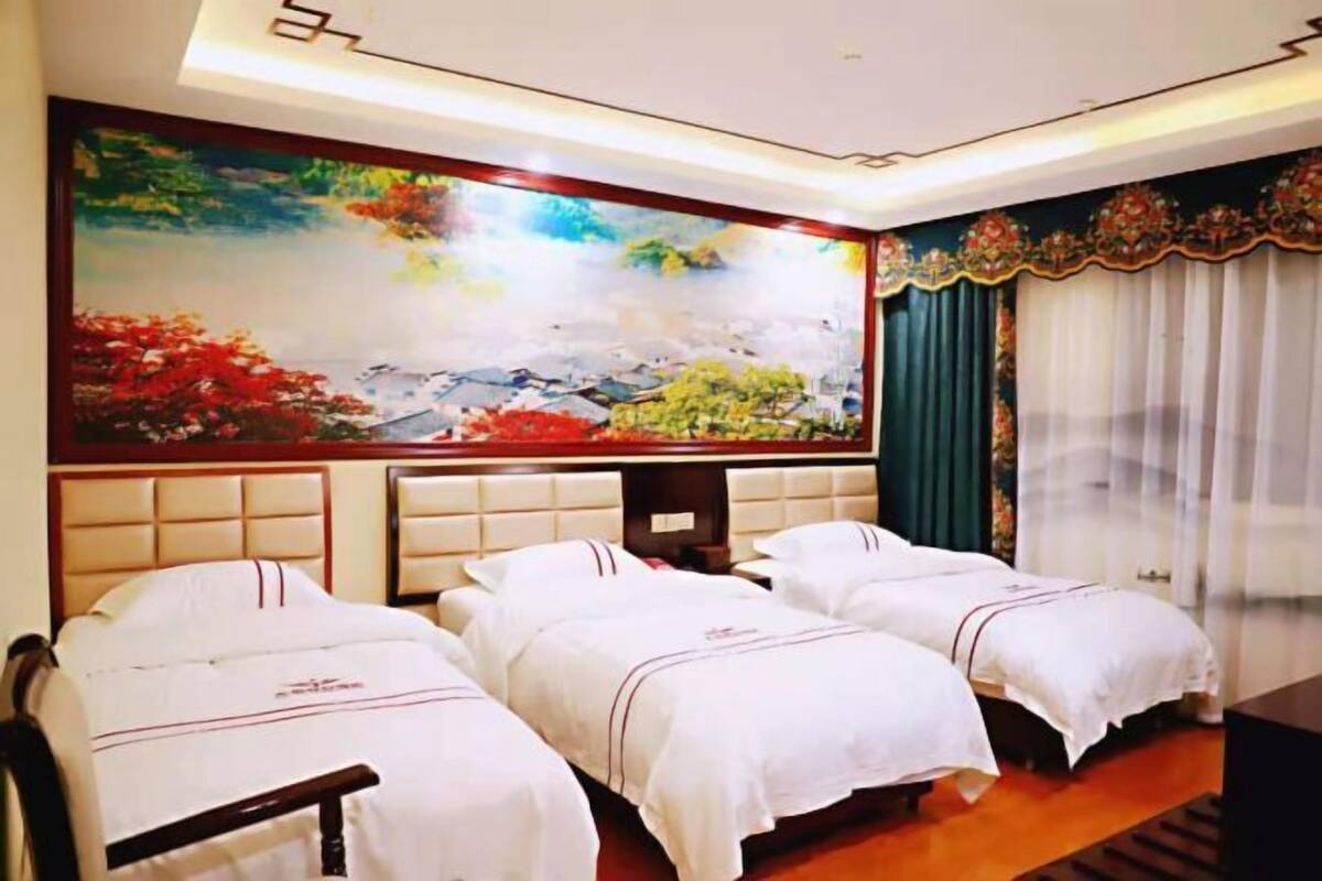 A hotel room with two beds, a large painting on the wall, and a view of a building outside.