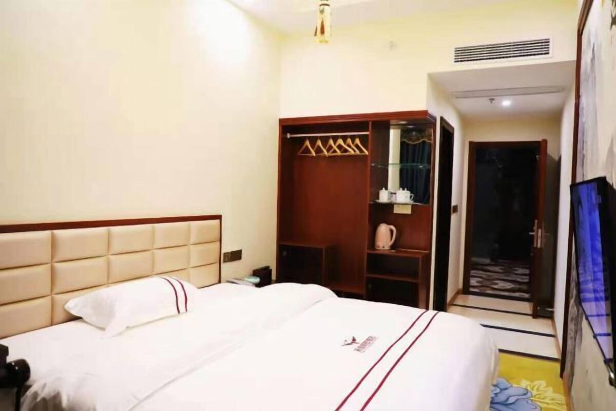 A hotel room with a bed, a wardrobe, a small table, and a television.