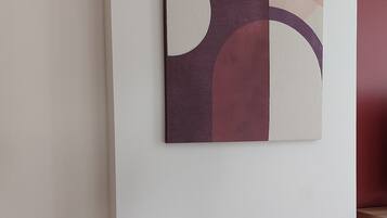 Een eettafel met helder glaswerk en borden, een witte placemat en een abstract kunstwerk aan de muur.