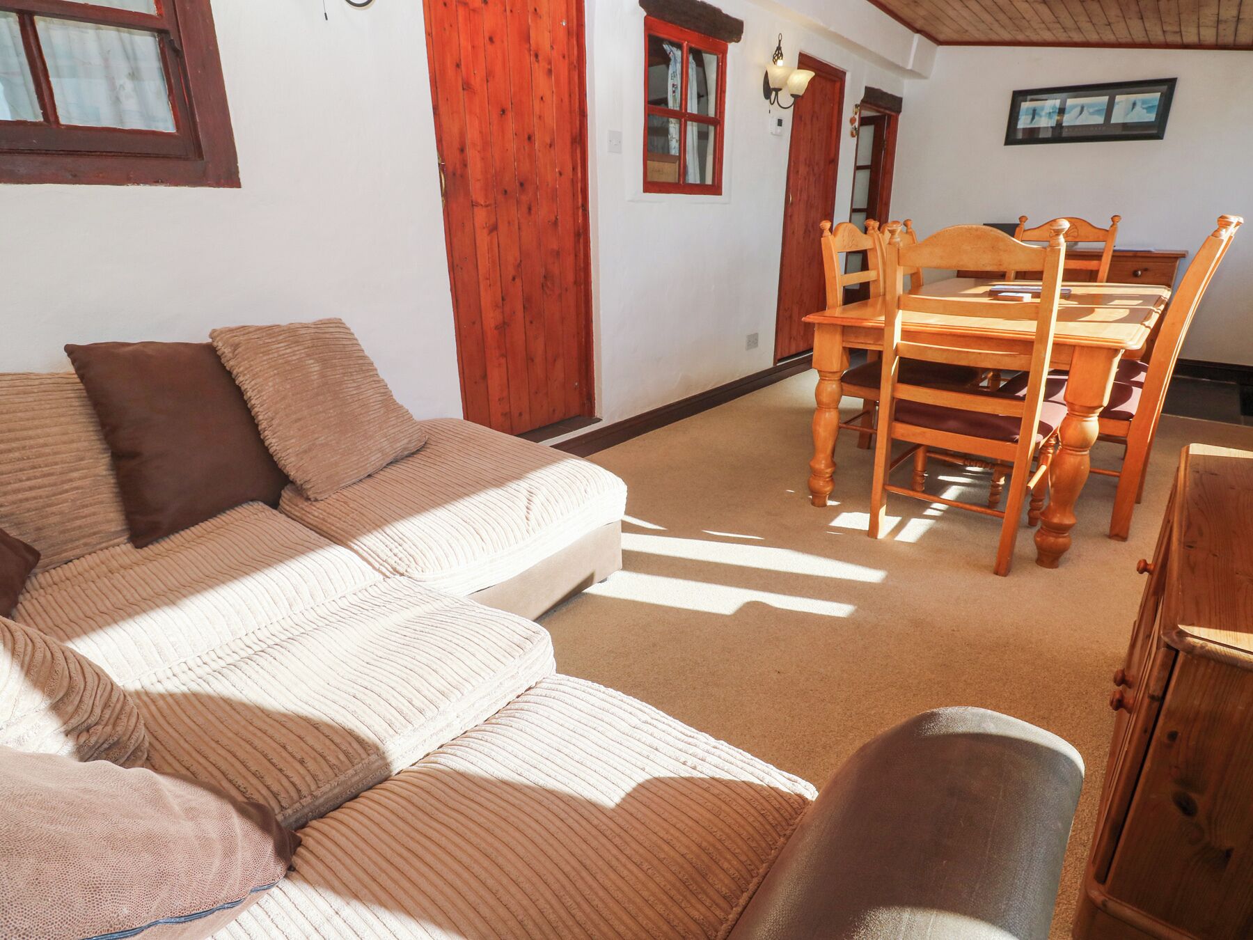 Ein gemütliches Wohnzimmer mit einer Couch, einem Esstisch mit Stühlen und einer Holzkommode.
