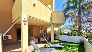 An outdoor patio with a dining area, a covered seating area, and a poolside lounge.