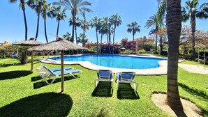 A swimming pool surrounded by palm trees and lounge chairs.