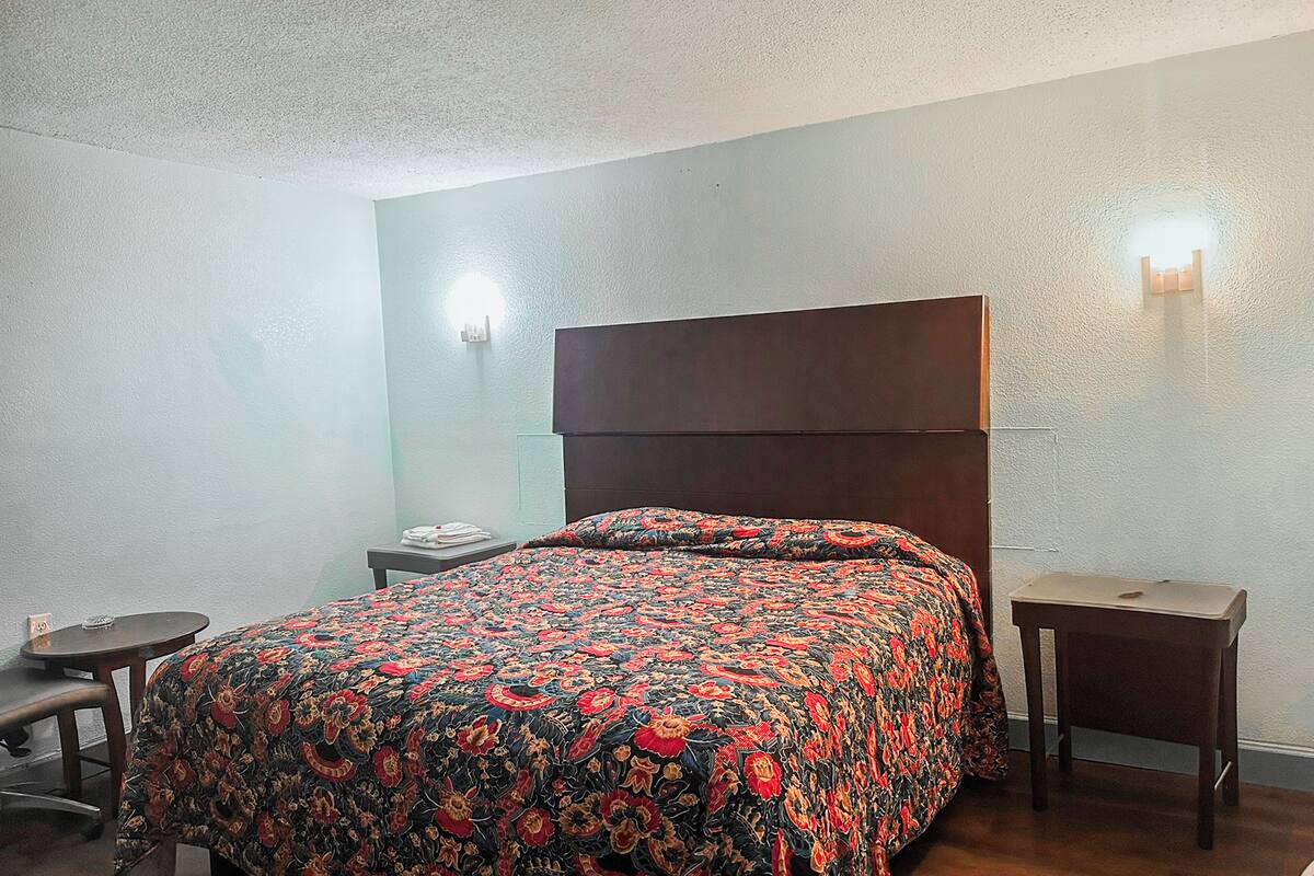 Una camera da letto con un letto, un comodino, una sedia e un lampadario a parete.