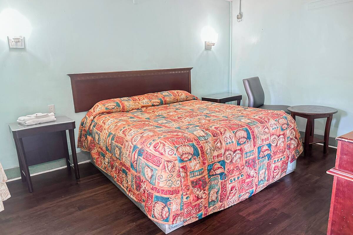 Una camera d'albergo con un letto grande, un tavolino, una sedia e una scrivania.