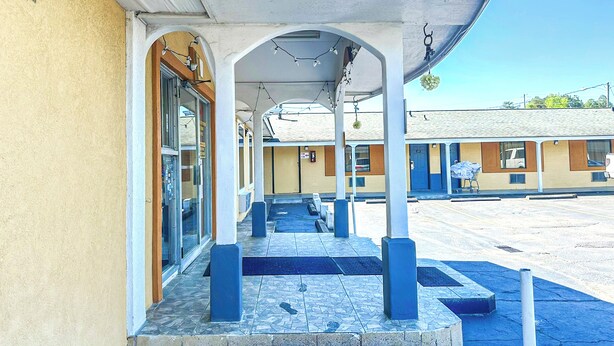 A covered outdoor area with a tiled floor, benches, and bollards. - OYO Hotel Jonesboro Near Atlanta Airport (Jonesboro)