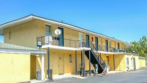 A yellow motel with a central staircase, a small balcony, and a single-story layout. - OYO Hotel Jonesboro Near Atlanta Airport (Jonesboro)