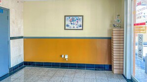 A hotel lobby with a tiled floor, a framed picture on the wall, and a small Christmas tree on a wooden stand. - OYO Hotel Jonesboro Near Atlanta Airport (Jonesboro)