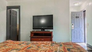 A hotel room with a bed, a television on a wooden stand, and two doors, one of which is labeled with the number 135. - OYO Hotel Jonesboro Near Atlanta Airport (Jonesboro)