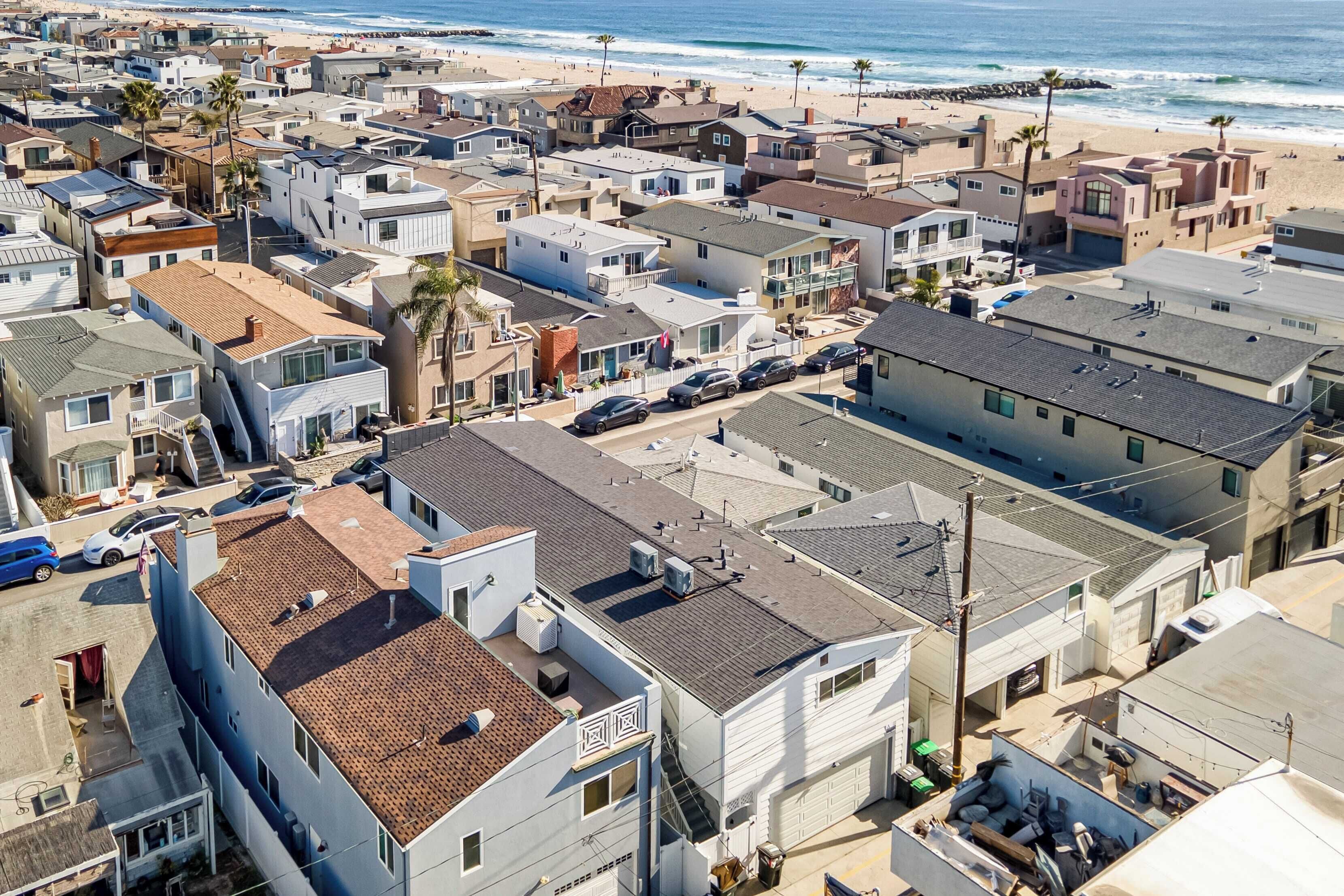 A coastal residential area with houses, a beach, and a rocky shoreline.