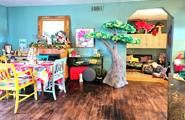 A dining area with a wooden table and chairs, a fireplace, and a large artificial tree. - Whimsical 3 bd cottage for families and pets. Sleeps 7, free wifi/snacks (Midwest City)
