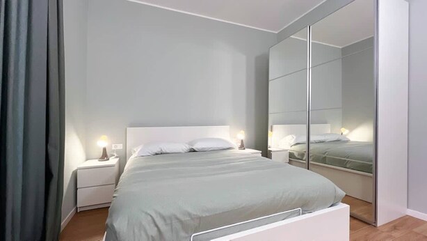 Une chambre à coucher moderne avec un lit, des tables de chevet et un grand miroir.