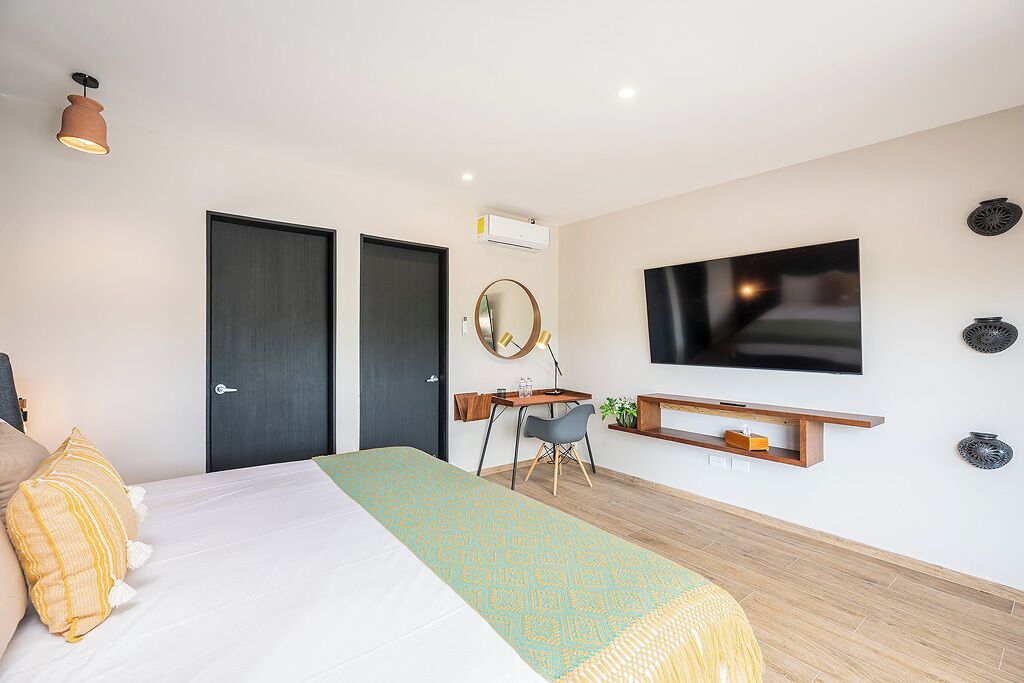 Ein modernes Hotelzimmer mit einem Bett, einem Schreibtisch, einem Sessel, einem Fernseher und einem an der Wand befestigten Regal.