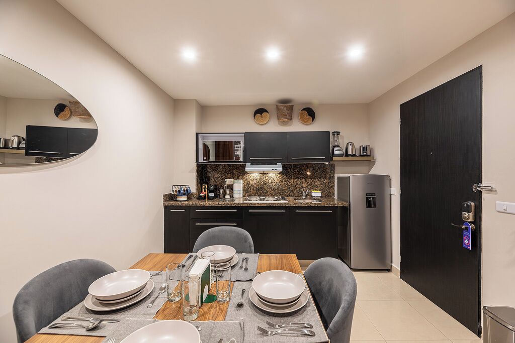 A modern kitchen with dark cabinets, a microwave, a refrigerator, and a dining area with a table set for four.