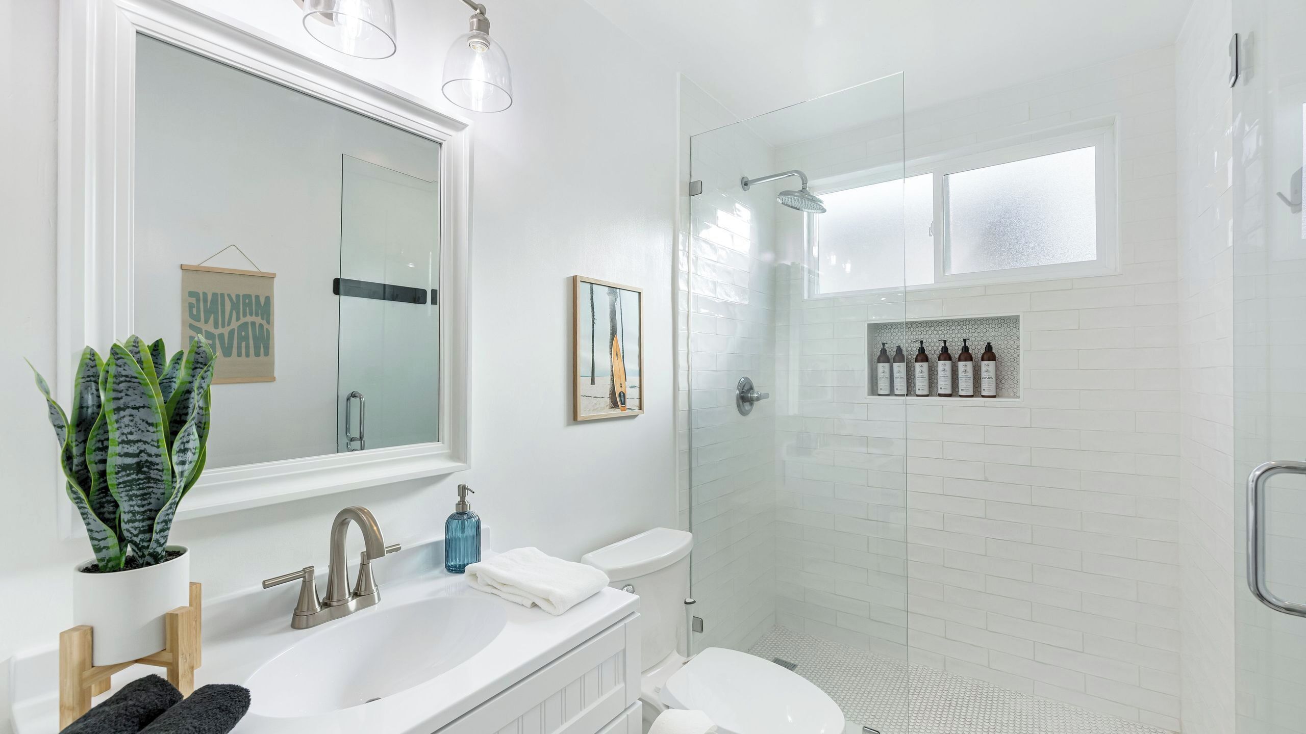 A modern bathroom with a glass-enclosed shower, a white sink, and a large mirror.