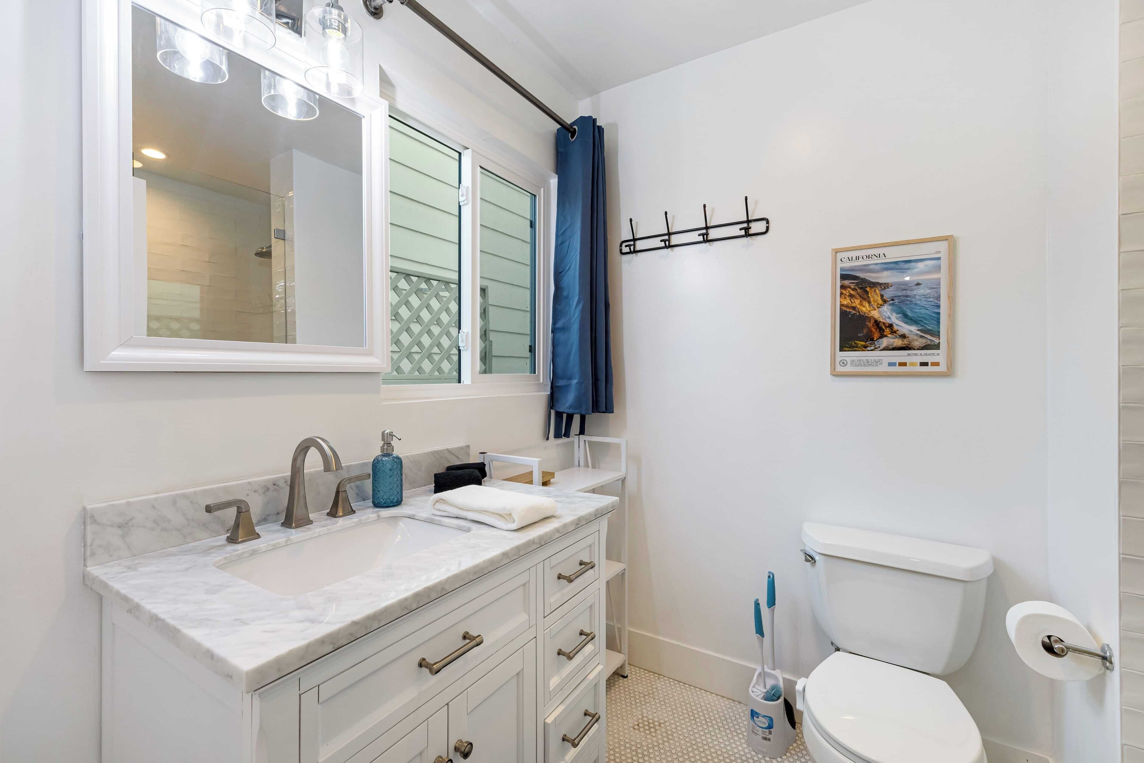 Une salle de bain avec un lavabo blanc, un miroir, des toilettes et un rideau de douche.