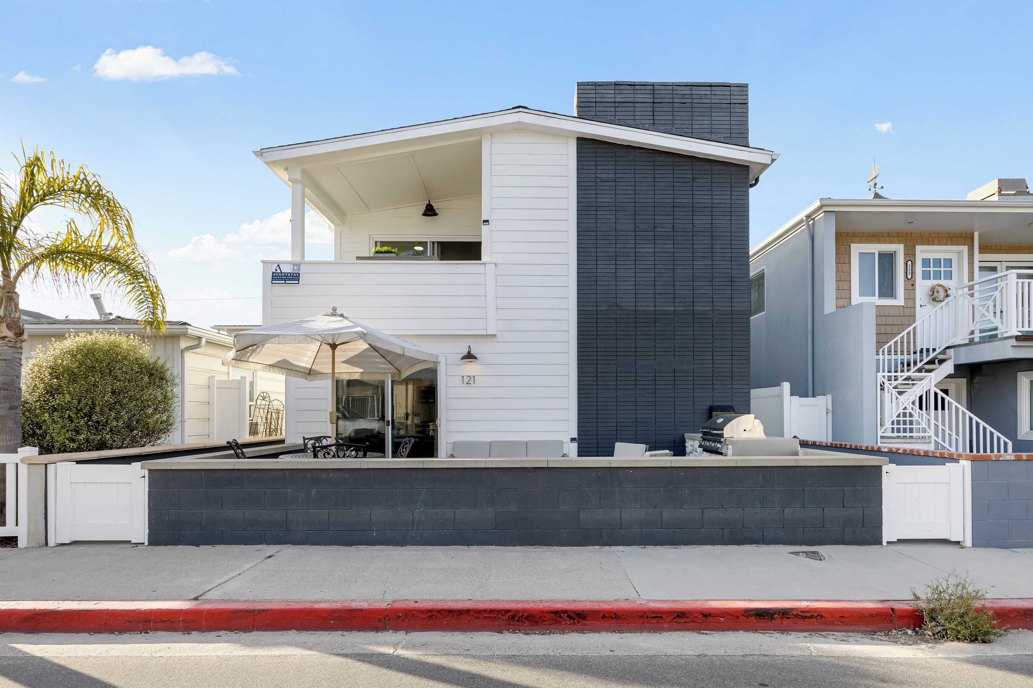 A modern two-story house with a covered patio, a garage, and a small balcony.