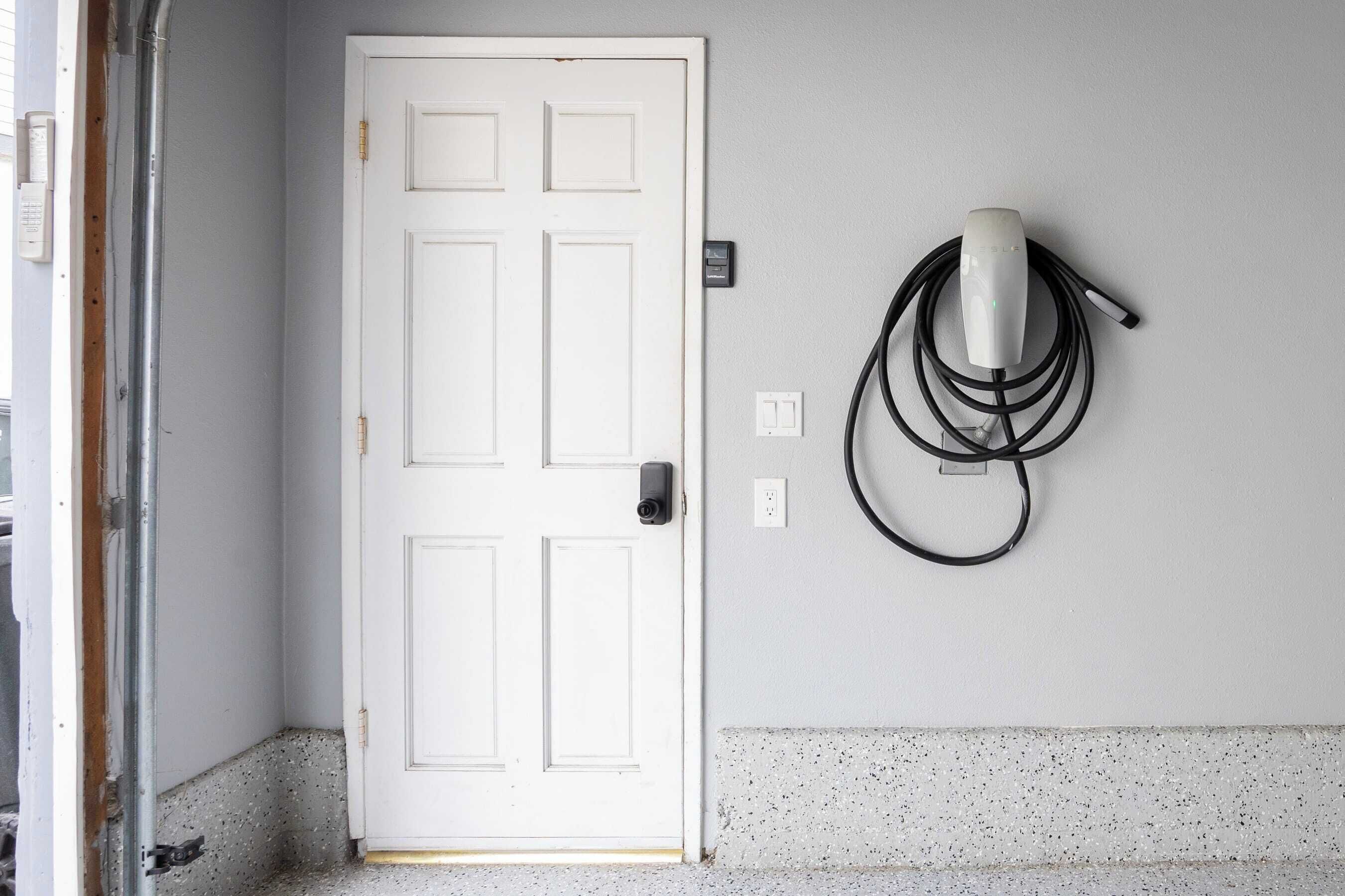 Una puerta blanca con una cámara de seguridad y un enchufe en la pared.