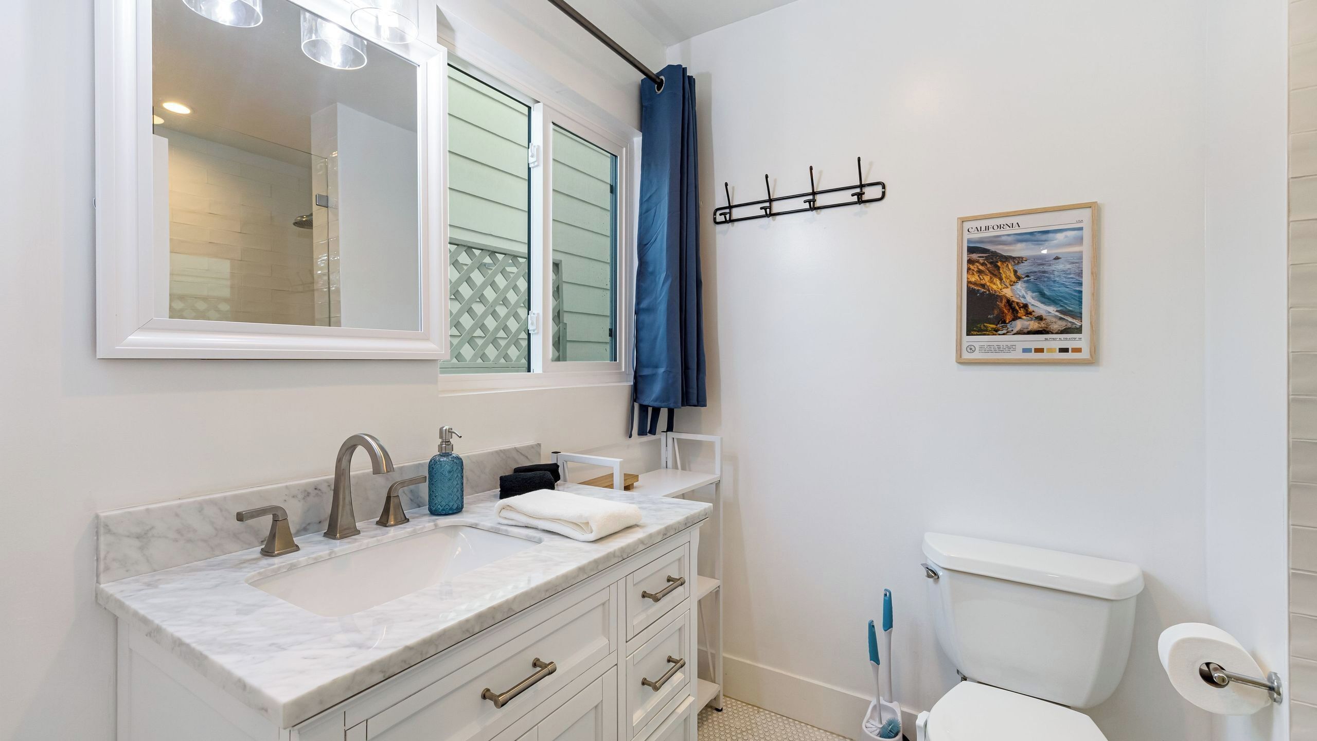 Un baño con lavamanos blanco, espejo, inodoro y cortina de ducha.