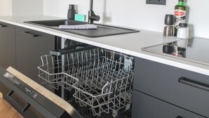Une cuisine moderne équipée d’un lave-vaisselle, d’un évier et d’un plan de travail.