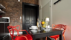 A modern kitchen with a brick wall, black cabinets, and red chairs. - Cracow Fancy Brick #1 – Old Town (Kraków)
