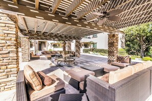 Une terrasse extérieure avec des meubles en osier, un mur en pierre et une fontaine.