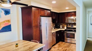 A modern kitchen with dark wooden cabinets, stainless steel appliances, and a wooden dining table.