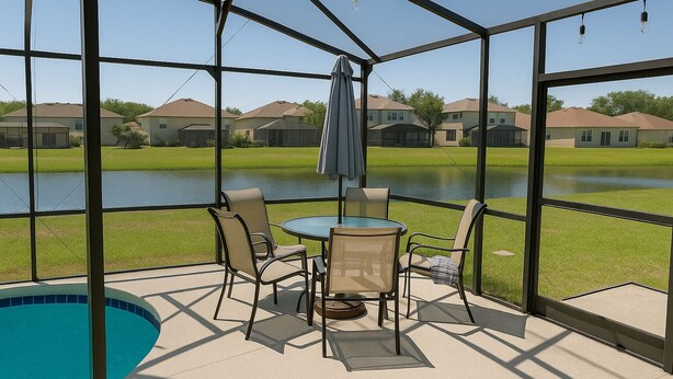 A covered patio with a pool, outdoor seating, and a view of a lake and houses. - Perfect Private Disney Vacation Getaway With Private Pool (Kissimmee)