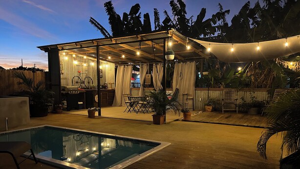 A pool area with a covered seating area, potted plants, and a bar. - El Camper with private pool (Maleza Alta)