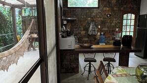A kitchen with a stone wall, a hanging light fixture, and a view of the outdoors through a large window.