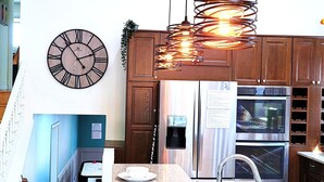 A modern kitchen with a central island, stainless steel appliances, wooden cabinets, and pendant lighting.