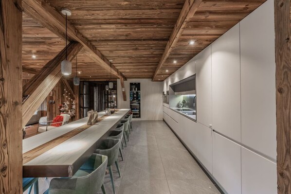 Eine moderne Küche mit einer langen Arbeitsplatte, weißen Schränken und Holzbalken an der Decke.